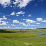 green fields under blue cloudy sky