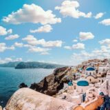 white concrete house near body of water under white and blue cloudy sky